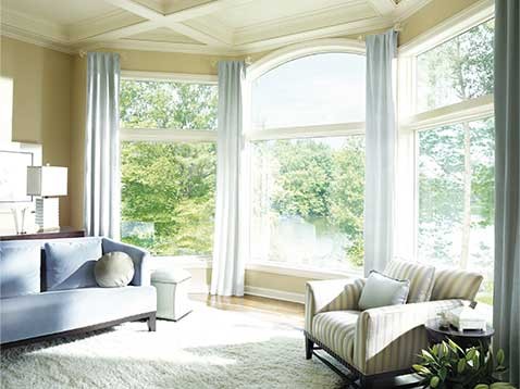 A living space with three large windows with drapes